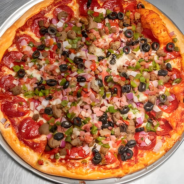 A close-up of a fully loaded Apna Pizza with pepperoni, olives, peppers, onions, and meats.